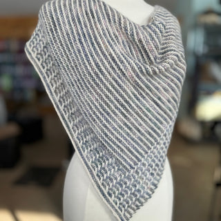 The hand knit Seeking Solace shawl draped on a mannequin